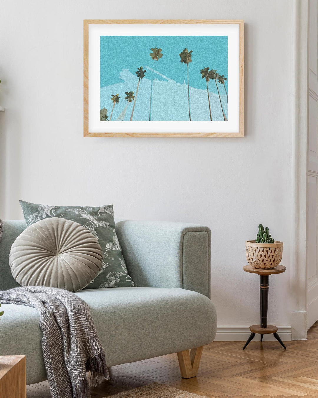 Living room with a gray sofa, decorative pillows, and a framed artwork of palm trees.