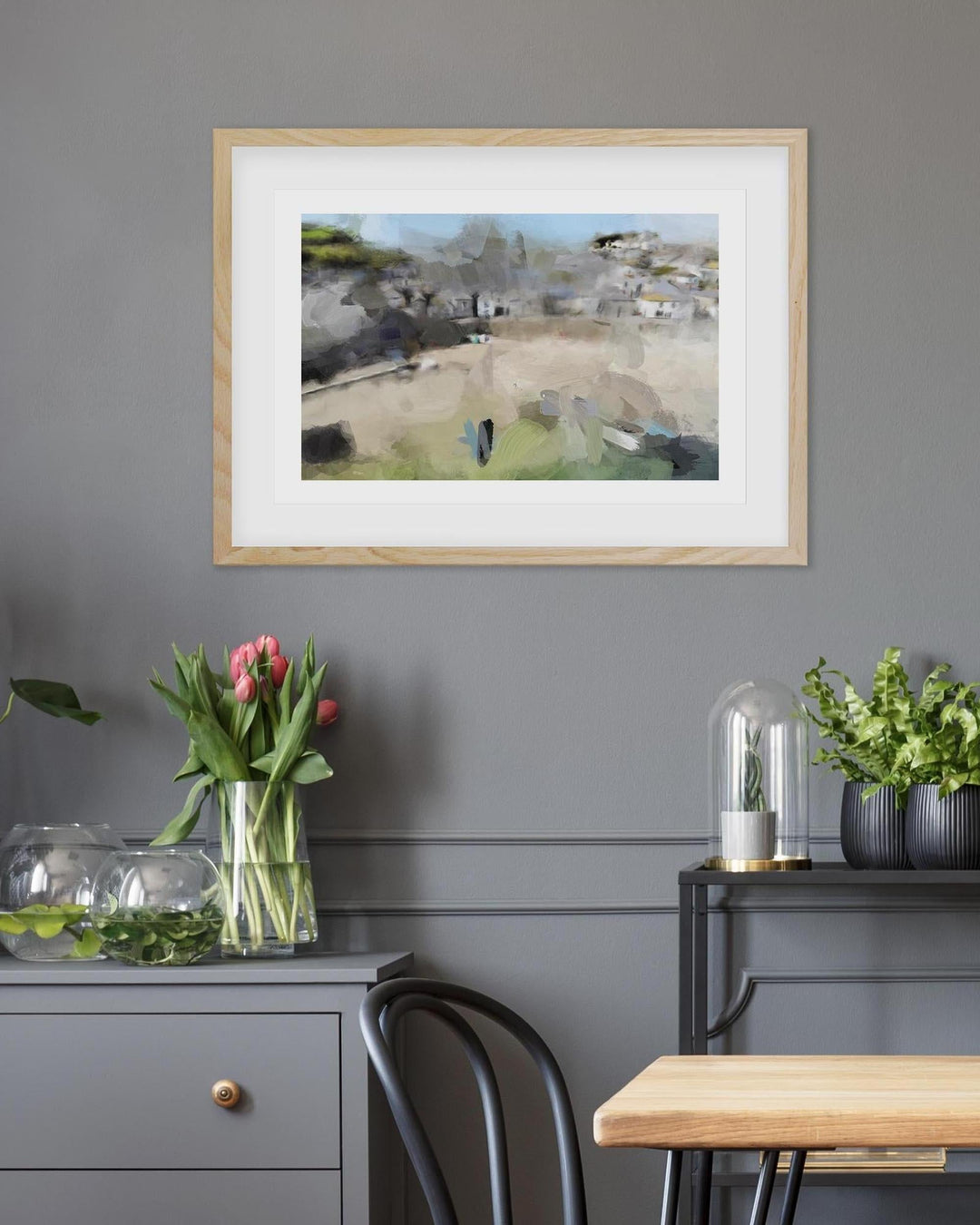 Framed artwork on a gray wall with decorative items below
