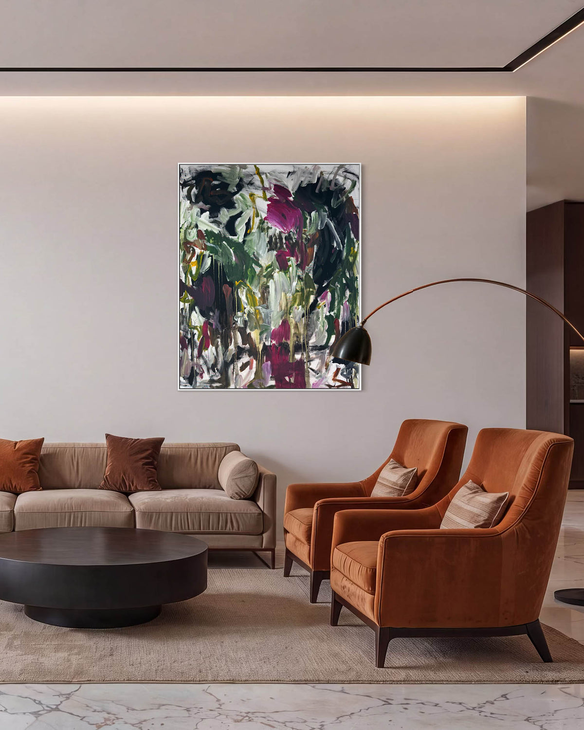 A modern living room featuring a square abstract wall art print with green, black, and purple brushstrokes, hung above a beige sofa and two rust-orange armchairs.