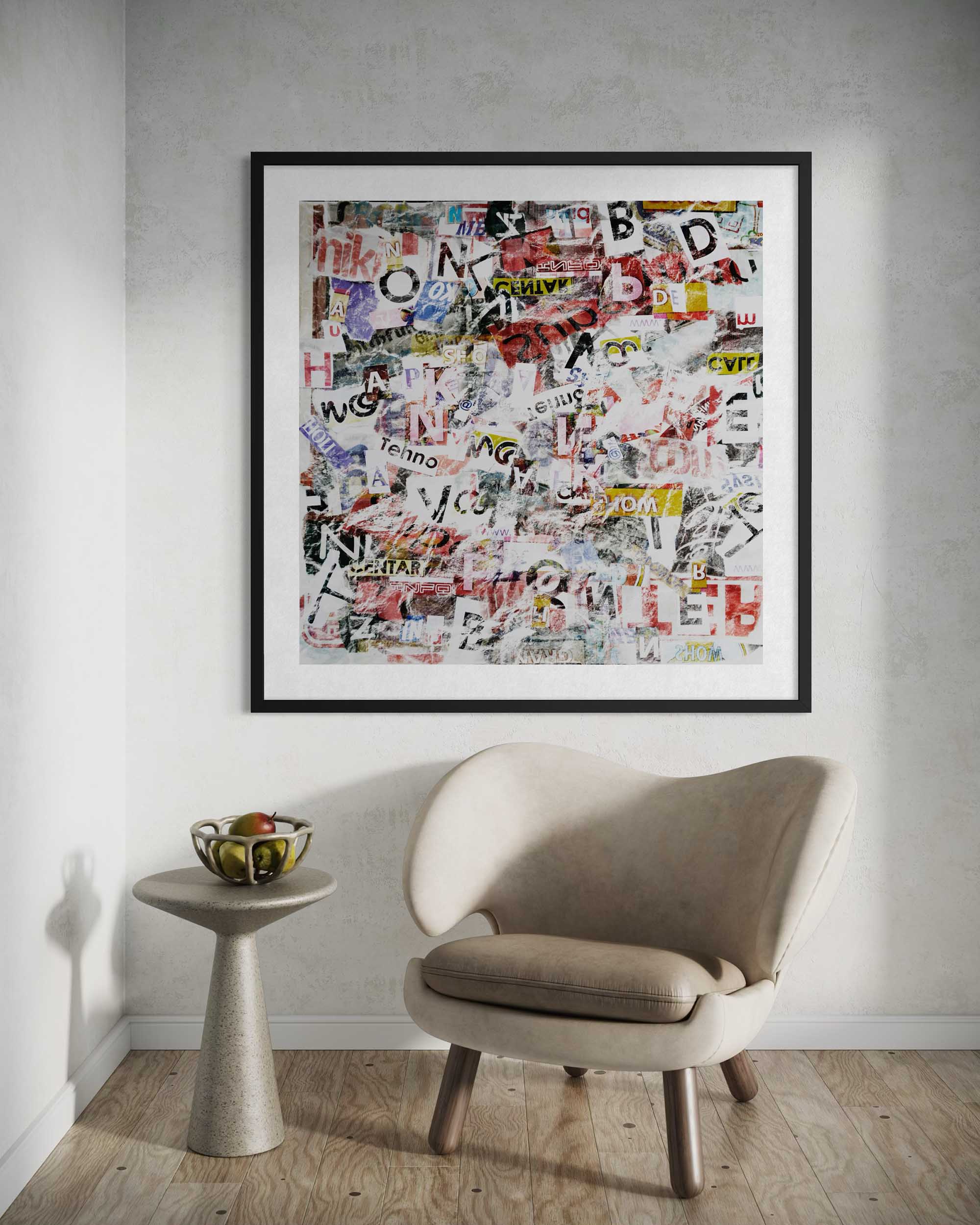 Framed collage art piece on a wall above a beige chair and small table.