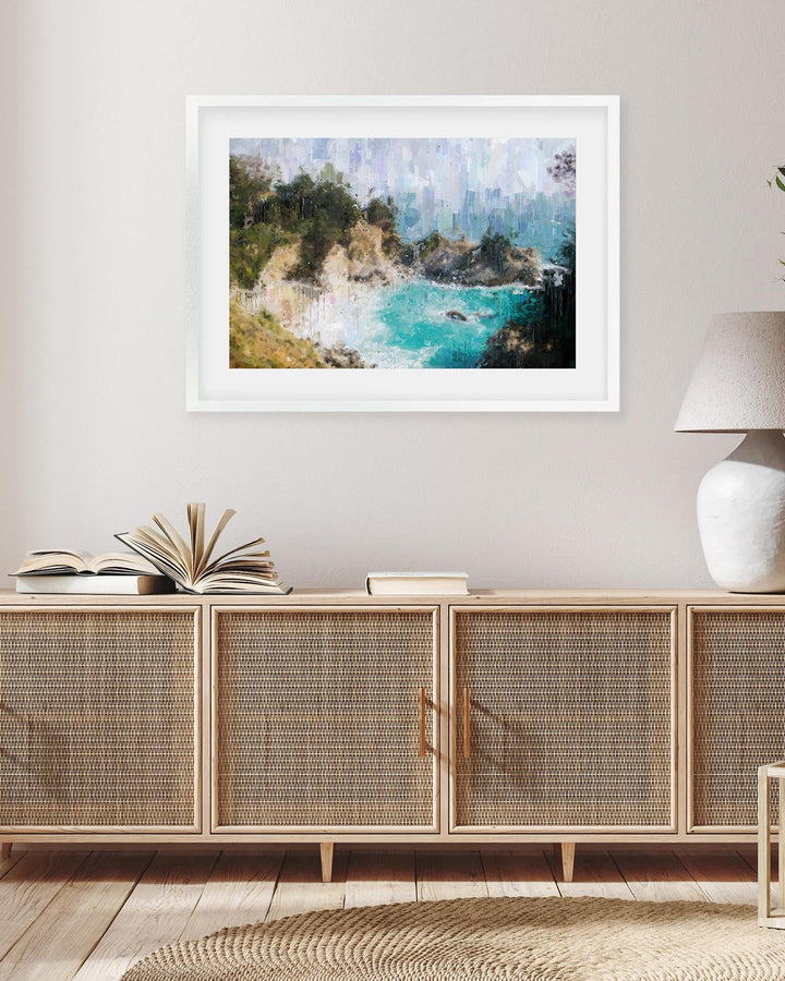 Framed artwork of a coastal scene above a wooden cabinet with rattan doors.