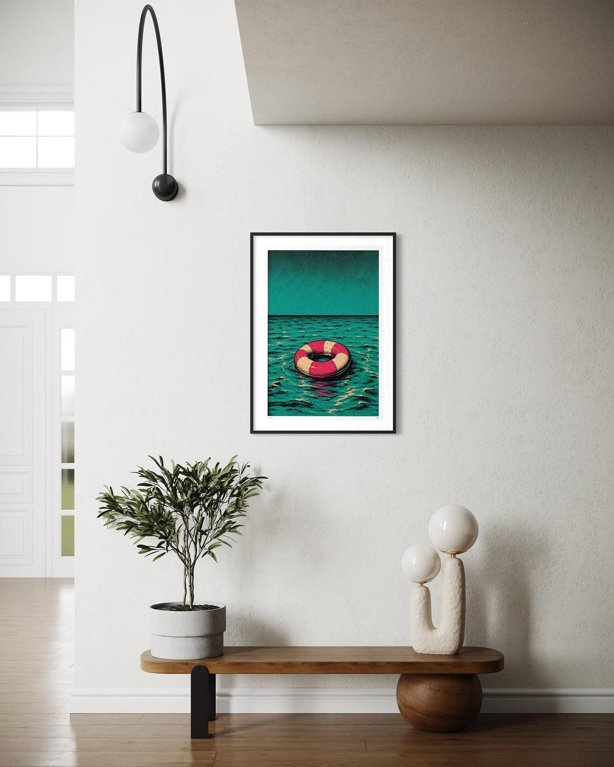 A framed art print featuring a pink life preserver floating on teal water, displayed on a white wall above a wooden bench in a modern, minimalist living room.
