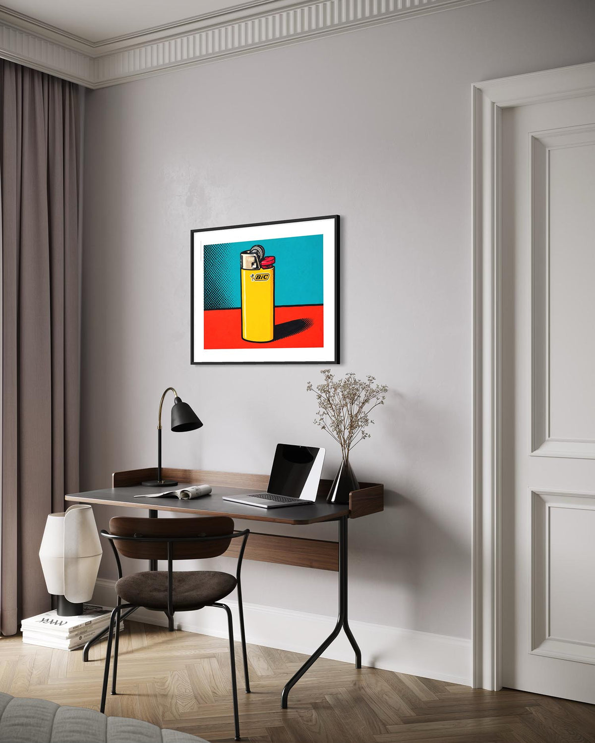 A framed pop art print featuring a yellow lighter on a turquoise and red background, displayed on a light gray wall above a modern desk in a styled home office.