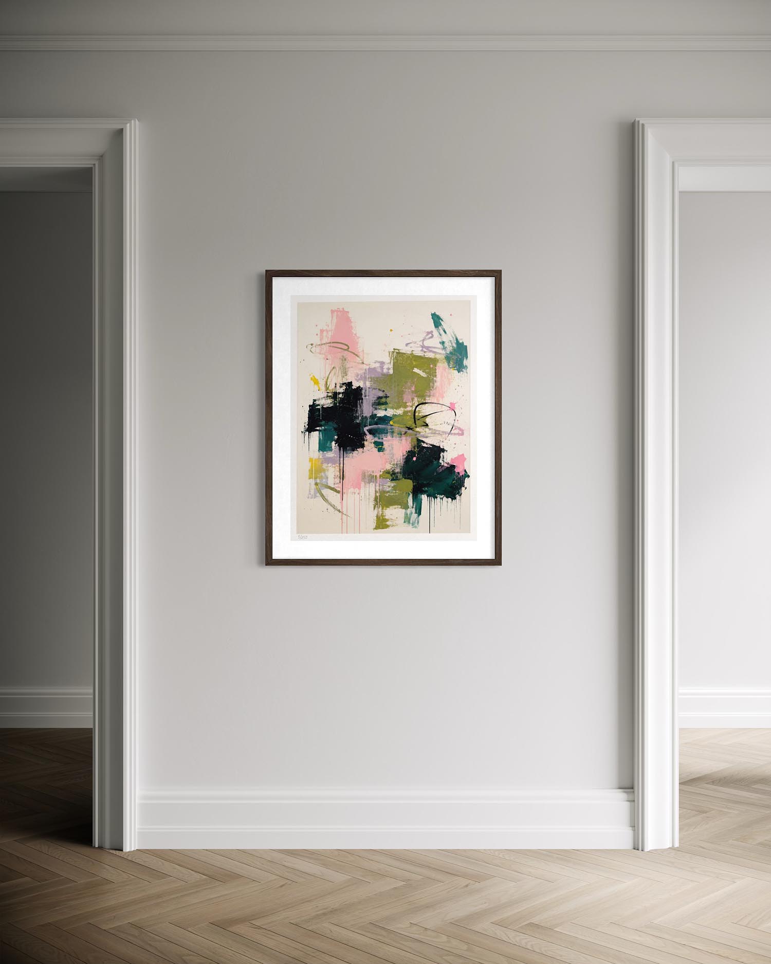 A framed abstract wall art print hangs on a light gray wall in a hallway with white trim and herringbone wood flooring. The artwork features abstract brushstrokes in pink, green, black, and teal on a light beige background.