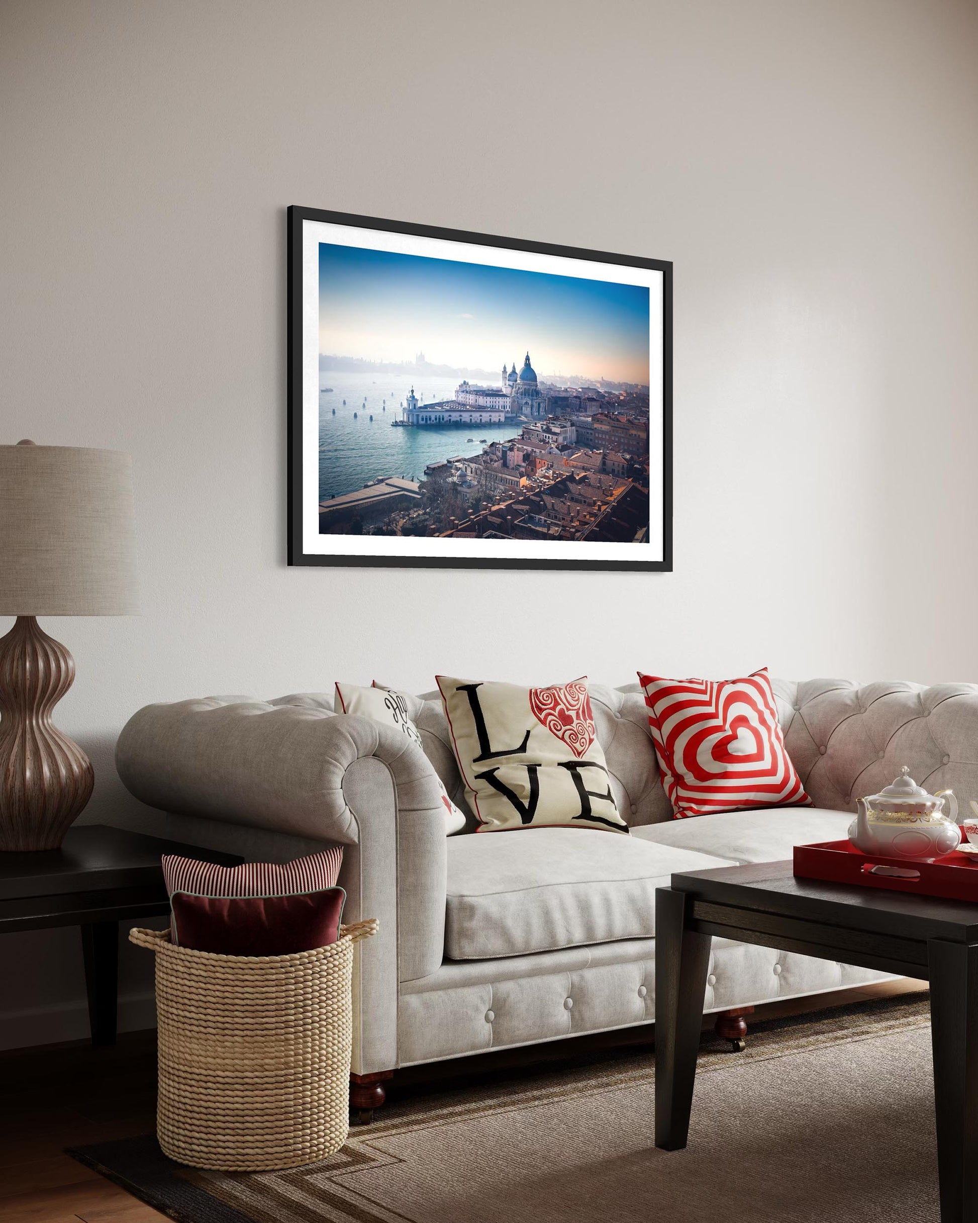 Living room with a framed picture of a cityscape on the wall, a couch with decorative pillows, and a lamp.