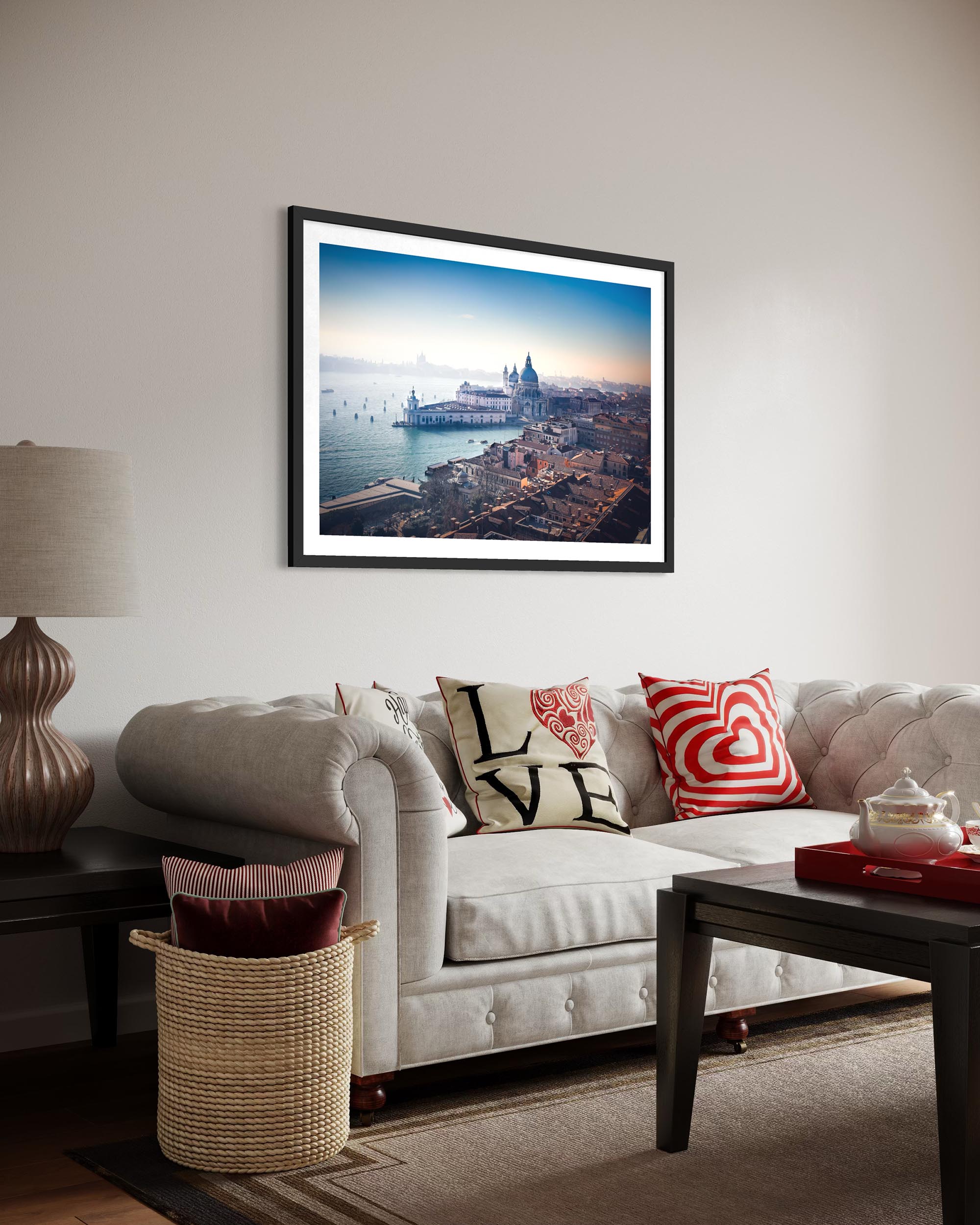 Living room with a framed picture of a cityscape on the wall, a couch with decorative pillows, and a lamp.