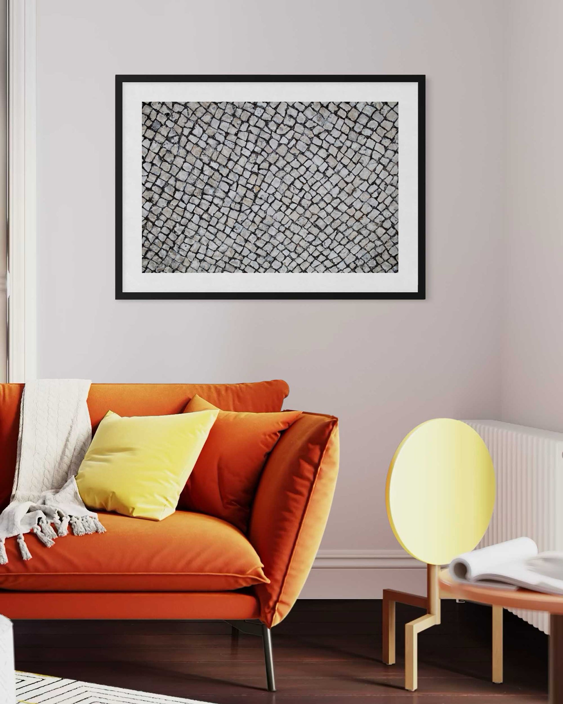 Living room with orange sofa, yellow chair, and framed abstract art on the wall.