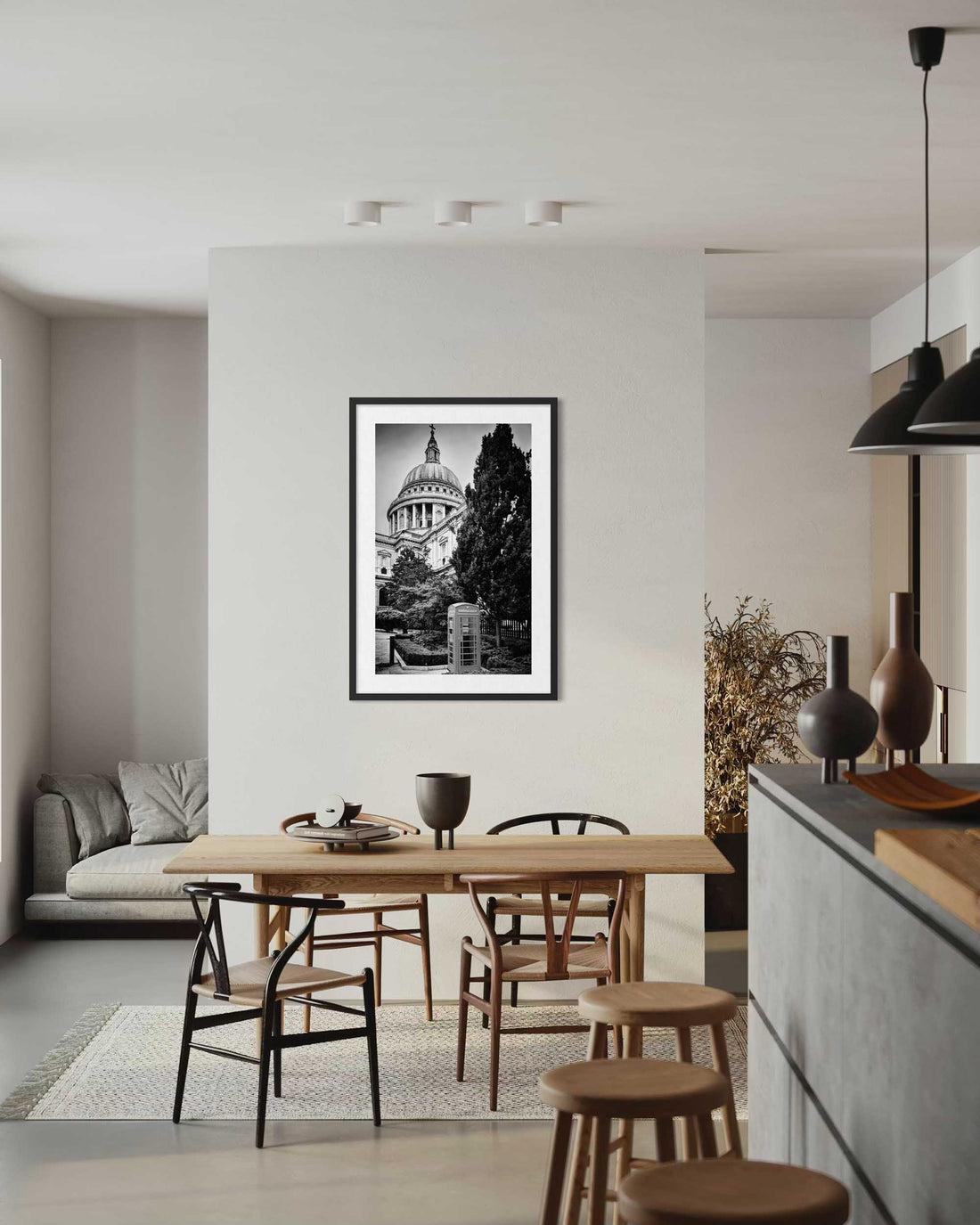Modern kitchen with wooden dining table and chairs, framed black and white artwork on wall.