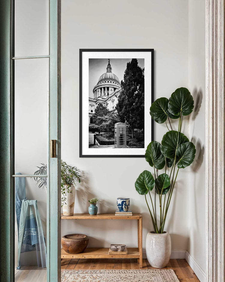 Framed black and white photo of a cathedral on a wall in a room with plants and decor.