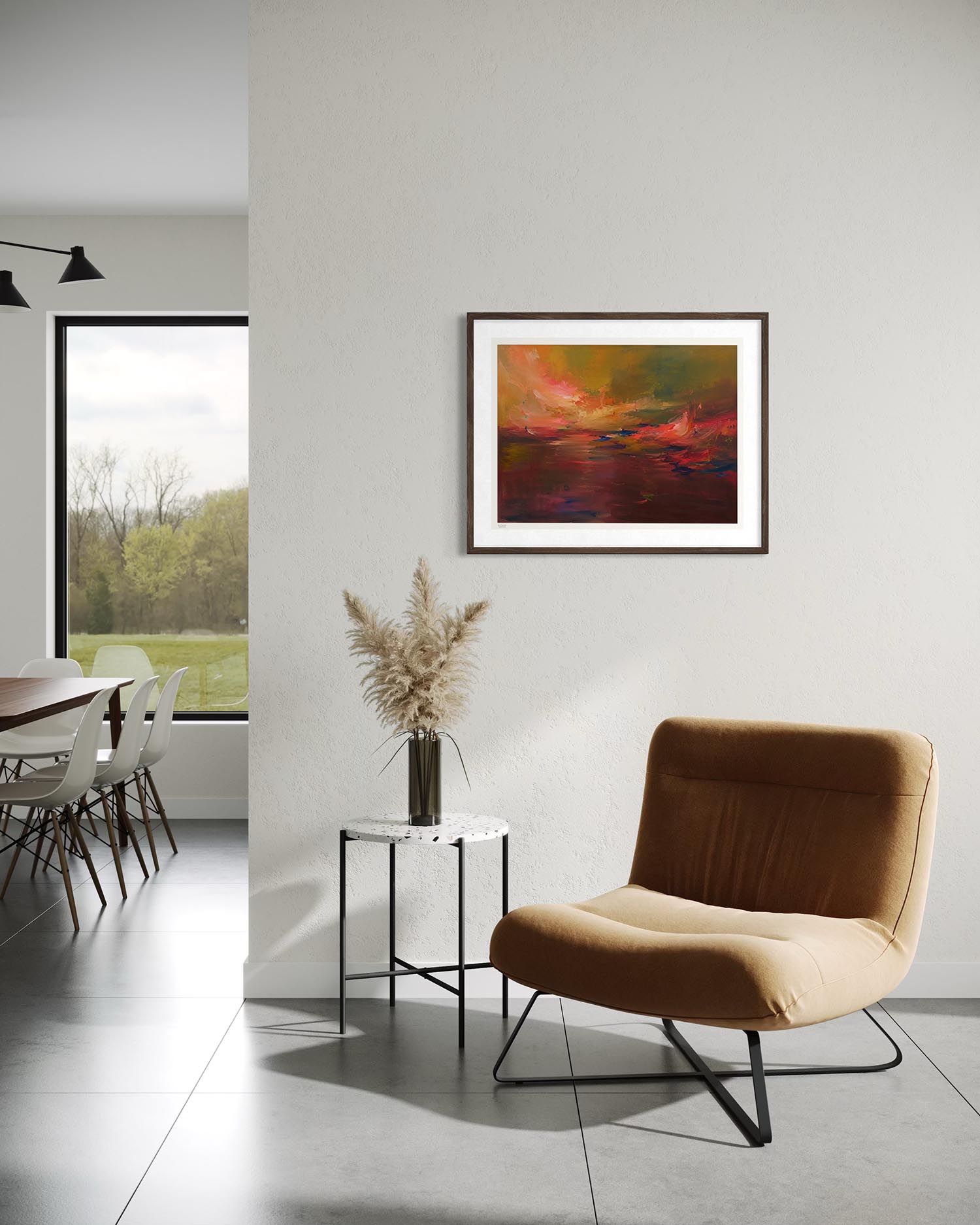 A framed abstract landscape painting with vibrant orange, red, and green tones hangs on a light gray wall in a modern living space with a brown armchair and a small side table.