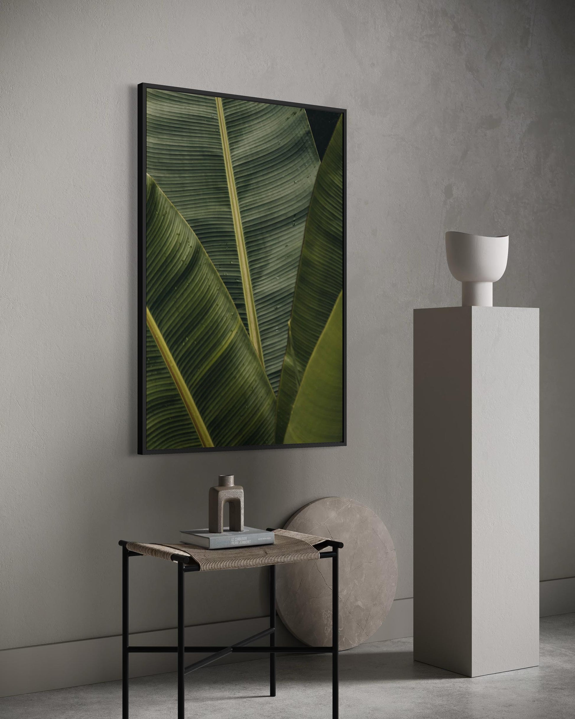 Framed artwork of a green leaf on a wall in a minimalistic room.