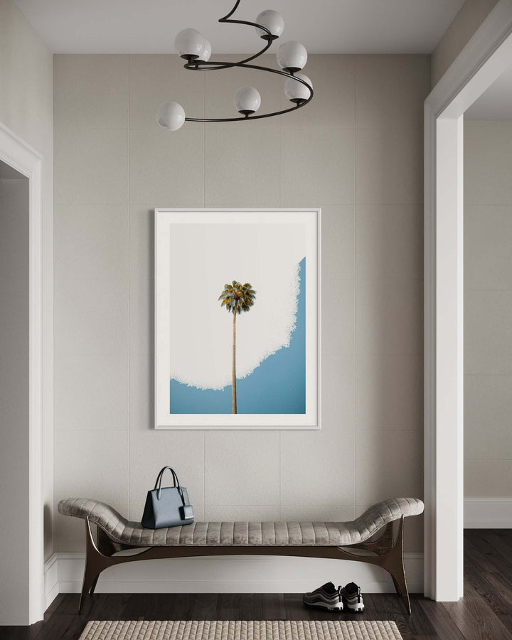 Framed artwork of a palm tree against a blue sky in a modern interior setting.