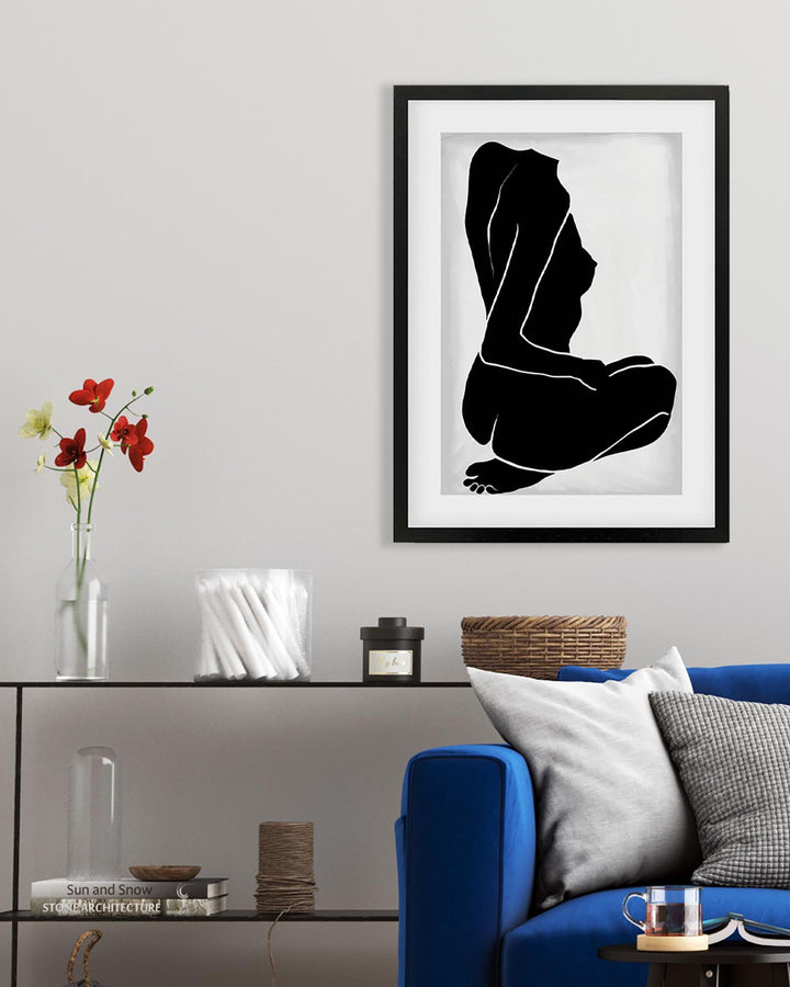 Framed black and white silhouette art print on a wall above a blue sofa.