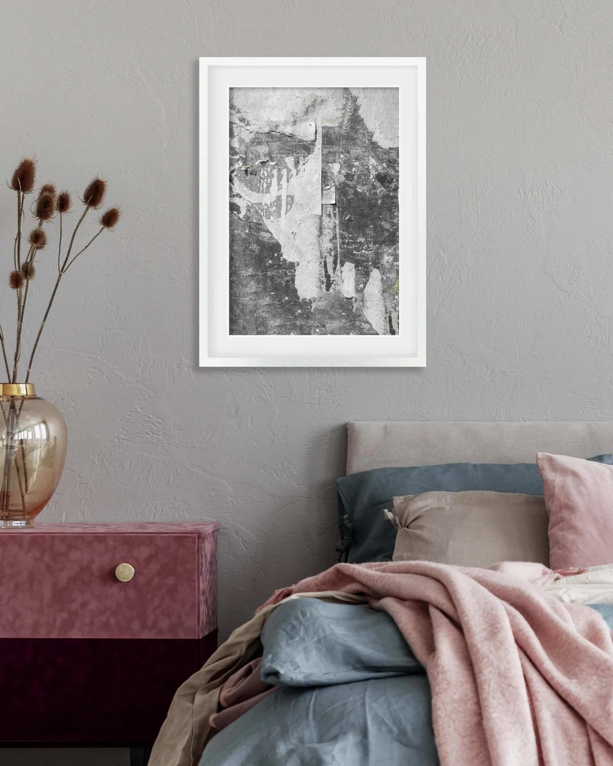 Framed artwork above a bed with pink and gray bedding.
