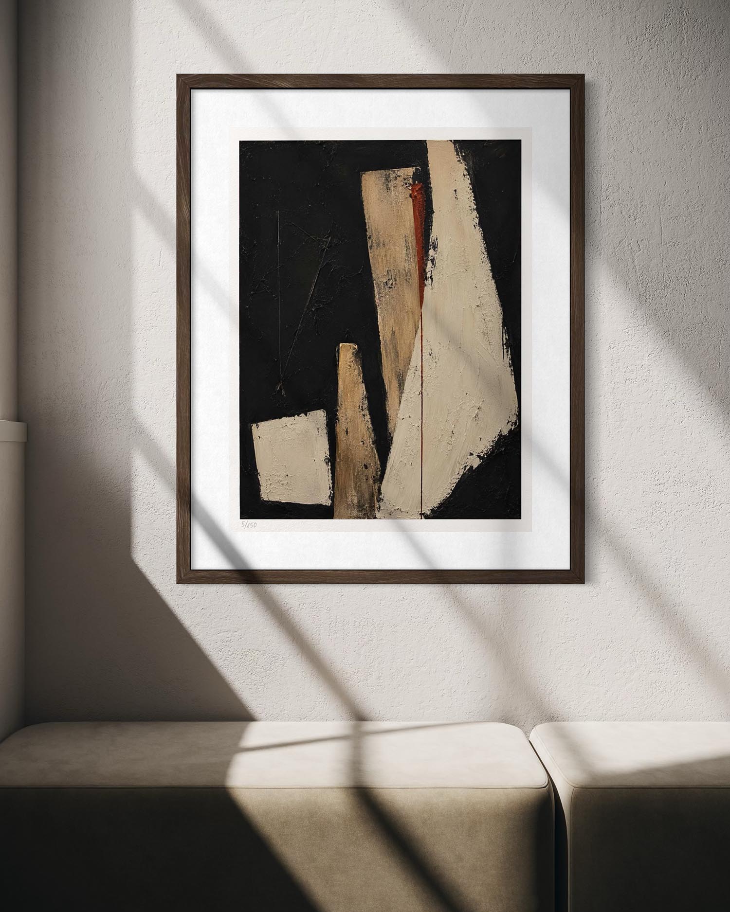 Framed abstract wall art hanging on a light wall above a sofa, with sunlight casting diagonal shadows across the print and furniture.
