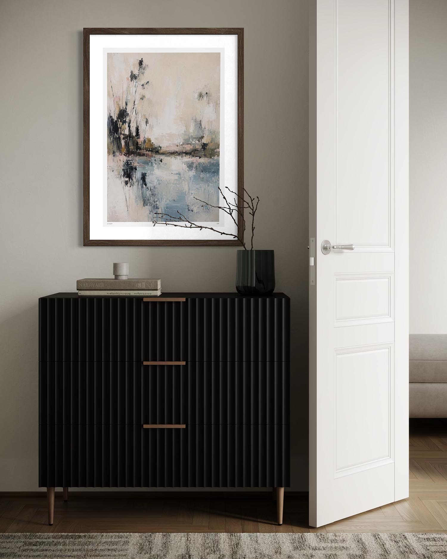 A framed abstract landscape art print with a white mat and dark wood frame hangs on a gray wall above a black ribbed console cabinet in a modern interior setting.