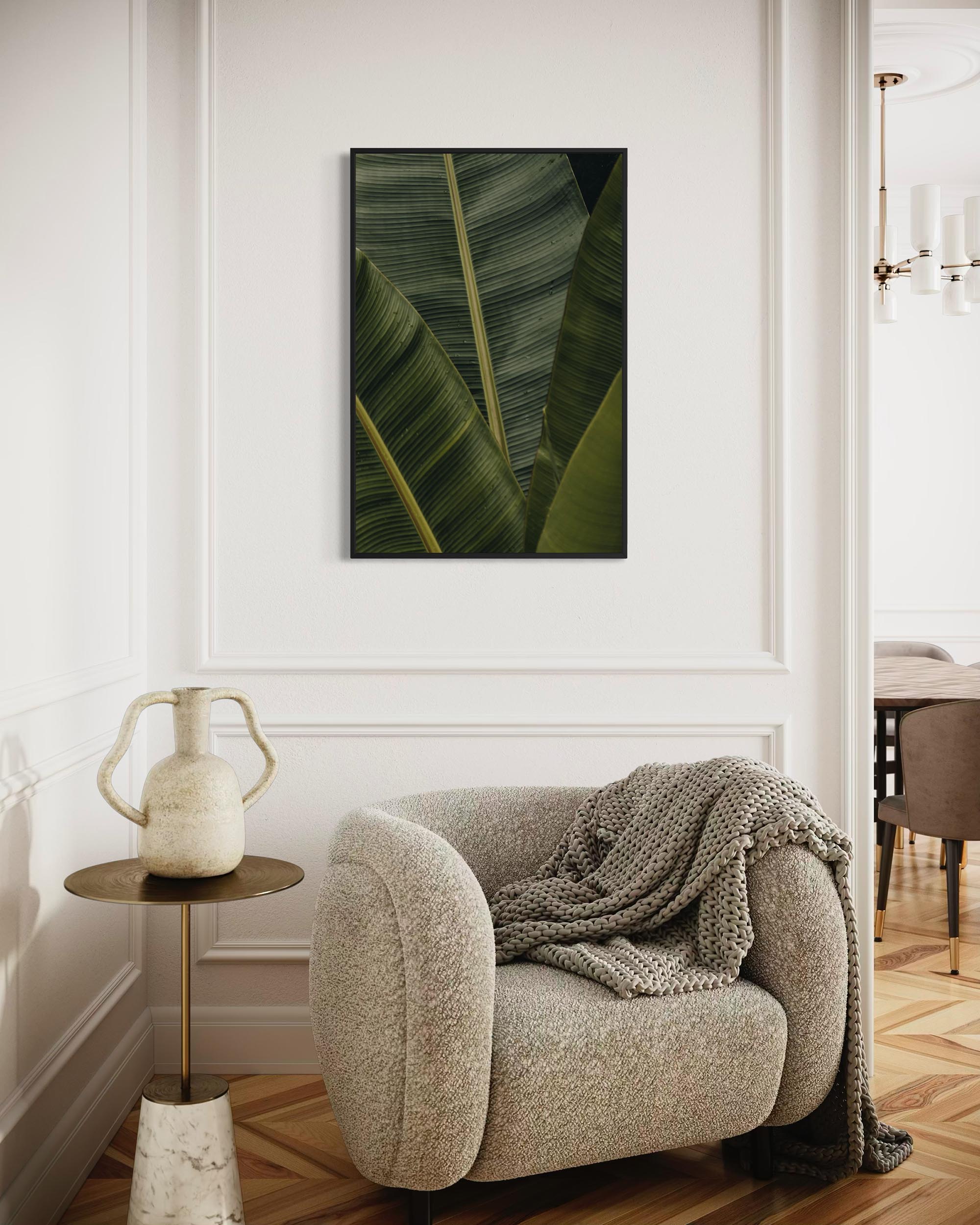 Modern interior with a beige armchair, side table, and wall art of green leaves.