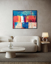 Modern living room with a colorful abstract painting on the wall, a beige sofa, and a side table with a lamp.