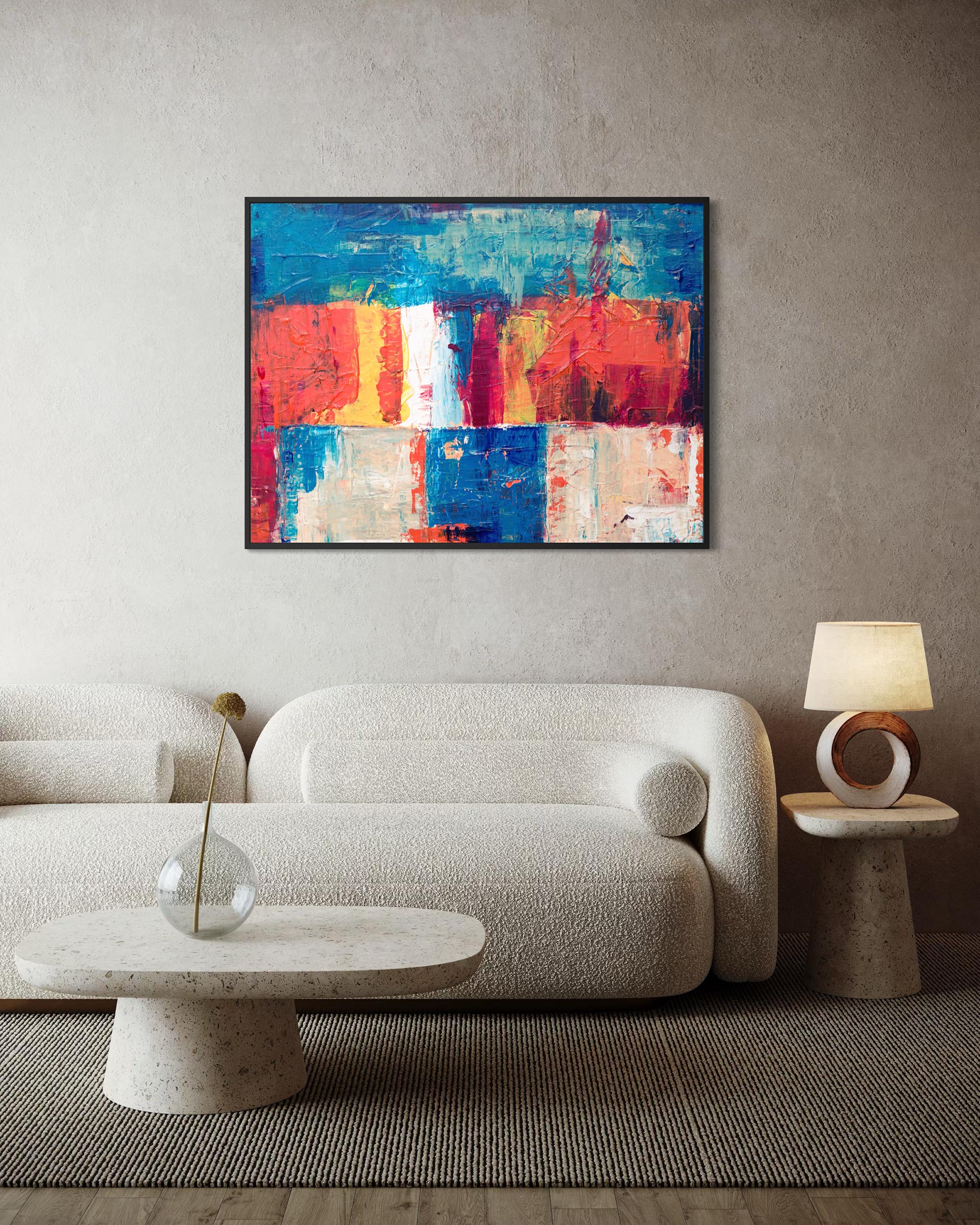 Modern living room with a colorful abstract painting on the wall, a beige sofa, and a side table with a lamp.