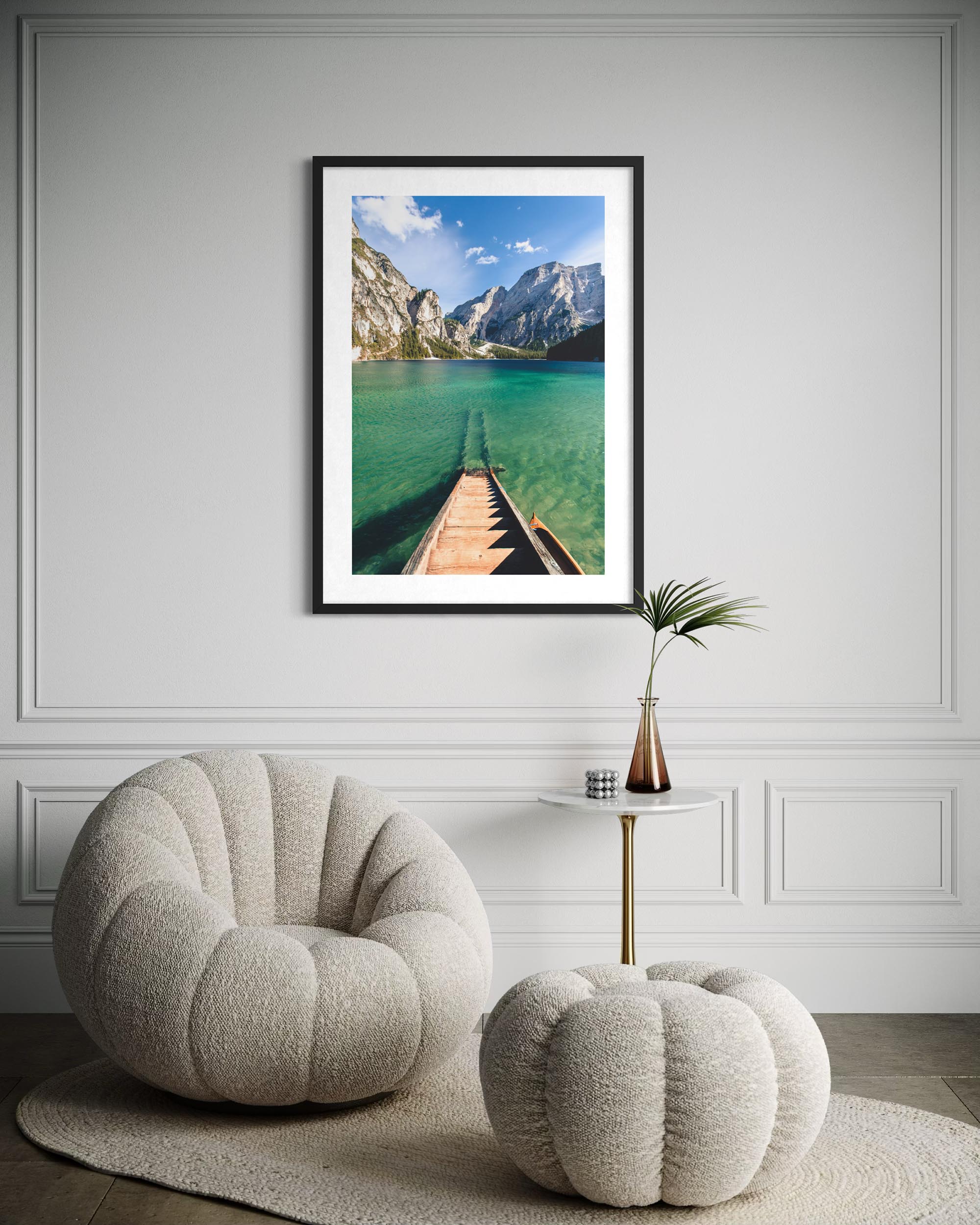 Framed photograph of a mountain lake on a wall above a textured armchair and ottoman.