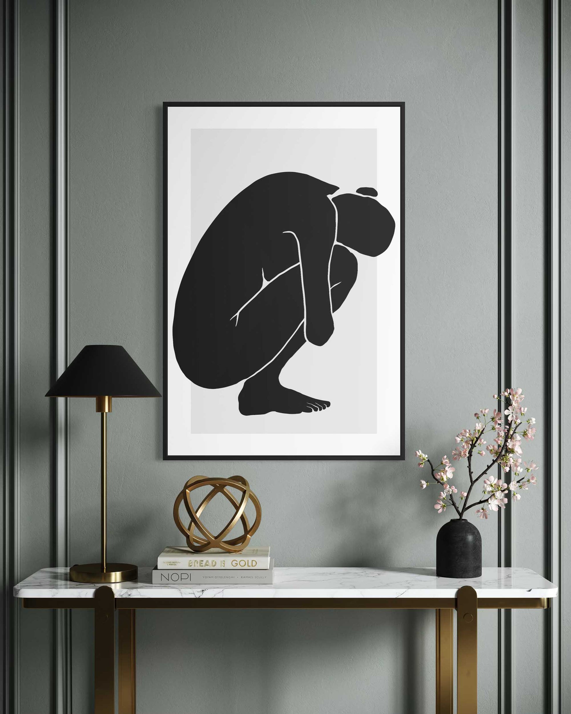 Framed abstract art of a black silhouette on a gray wall above a marble console table.