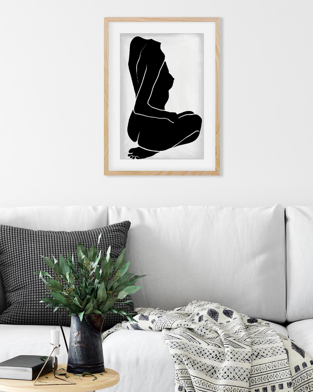 Framed black and white abstract art print on a wall above a sofa.