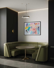 Modern interior with green curved sofa, round table, and abstract art on wall.