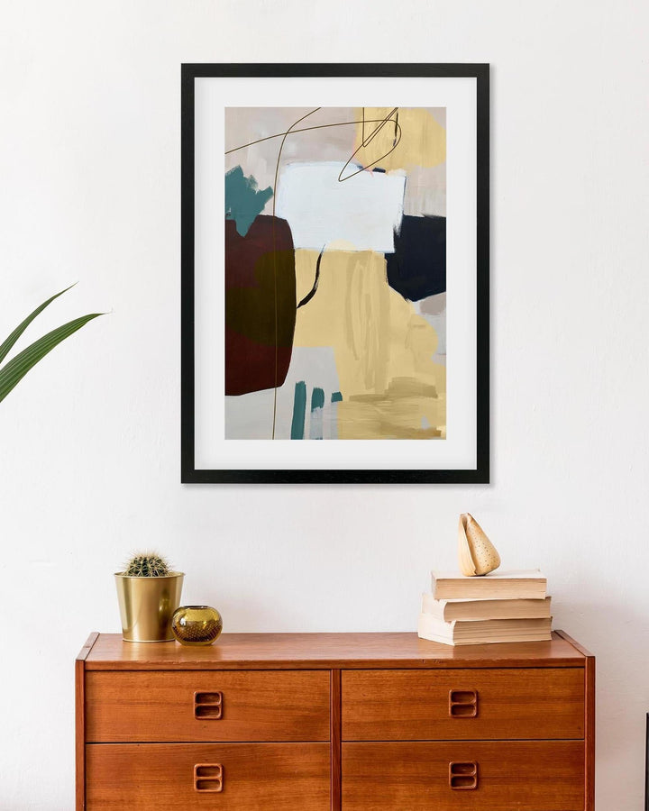 Abstract art print on a wall above a wooden dresser with decorative items.