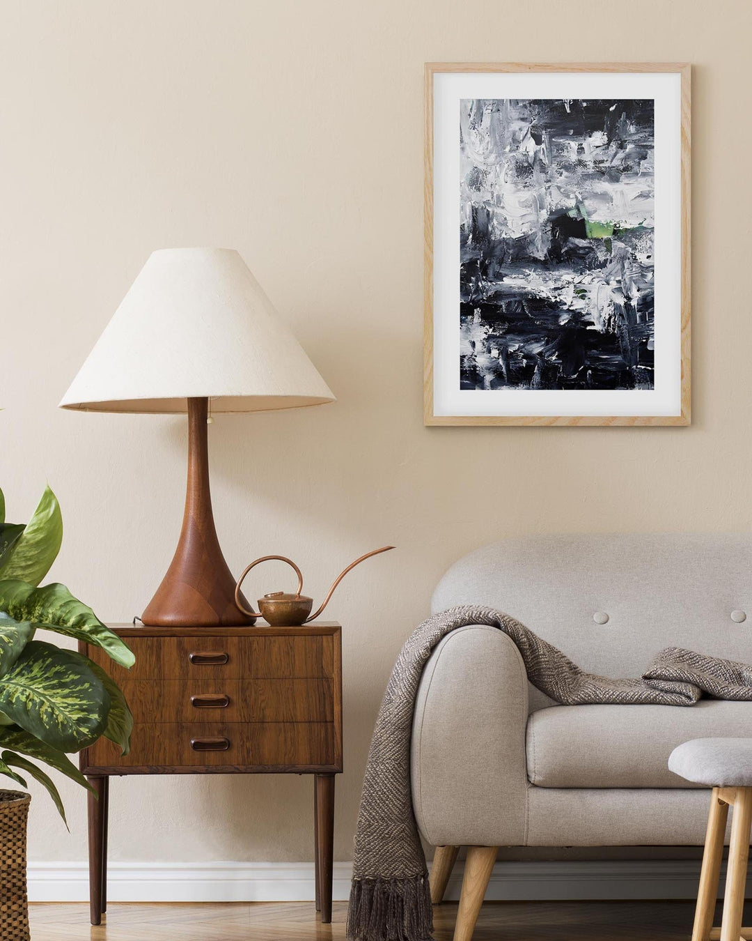 Living room with a lamp, side table, sofa, and abstract art on the wall.
