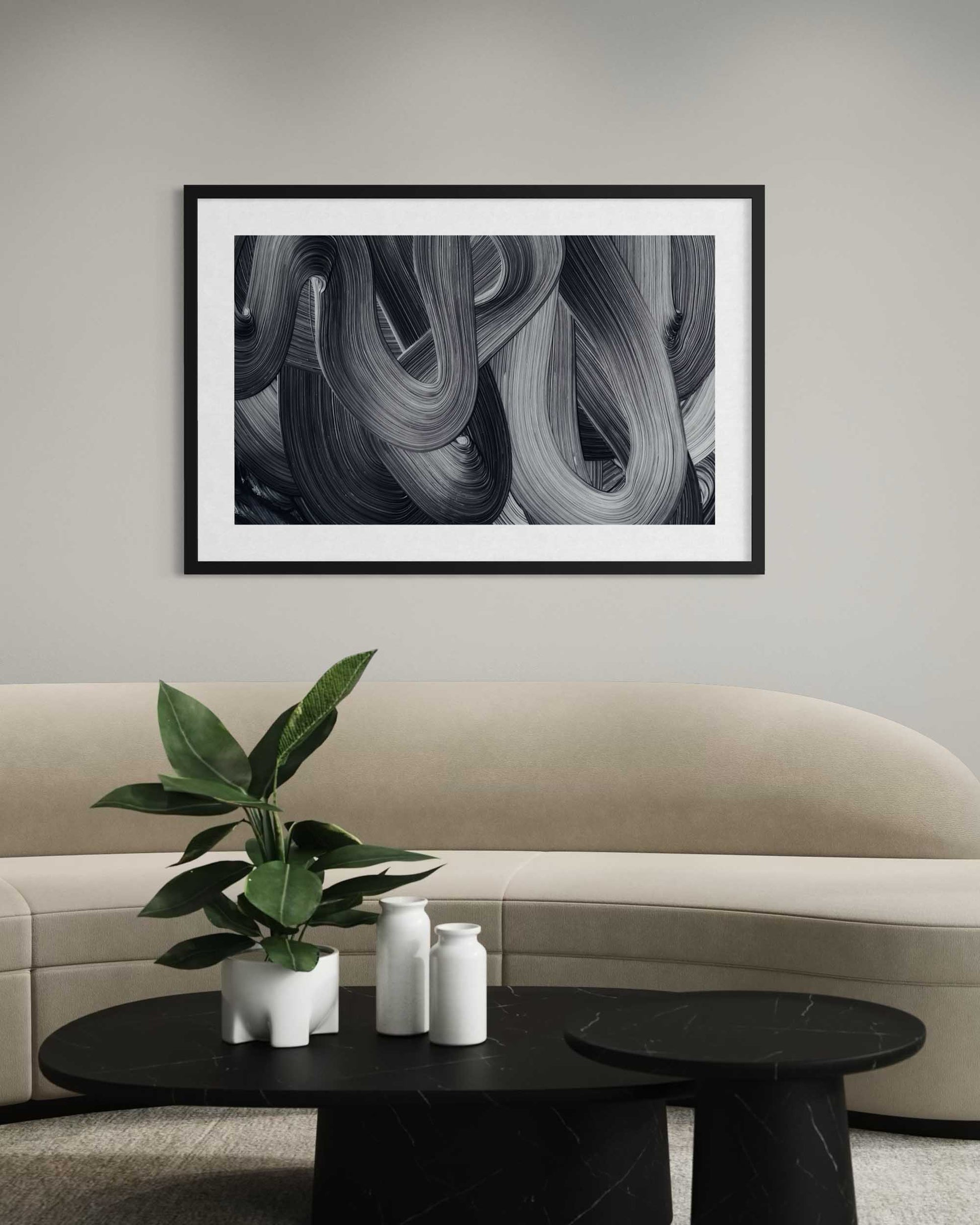 Framed abstract art above a beige sofa with a coffee table and plant