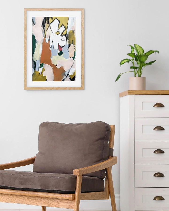 Modern interior with a brown cushioned chair, white dresser, and abstract art on the wall.