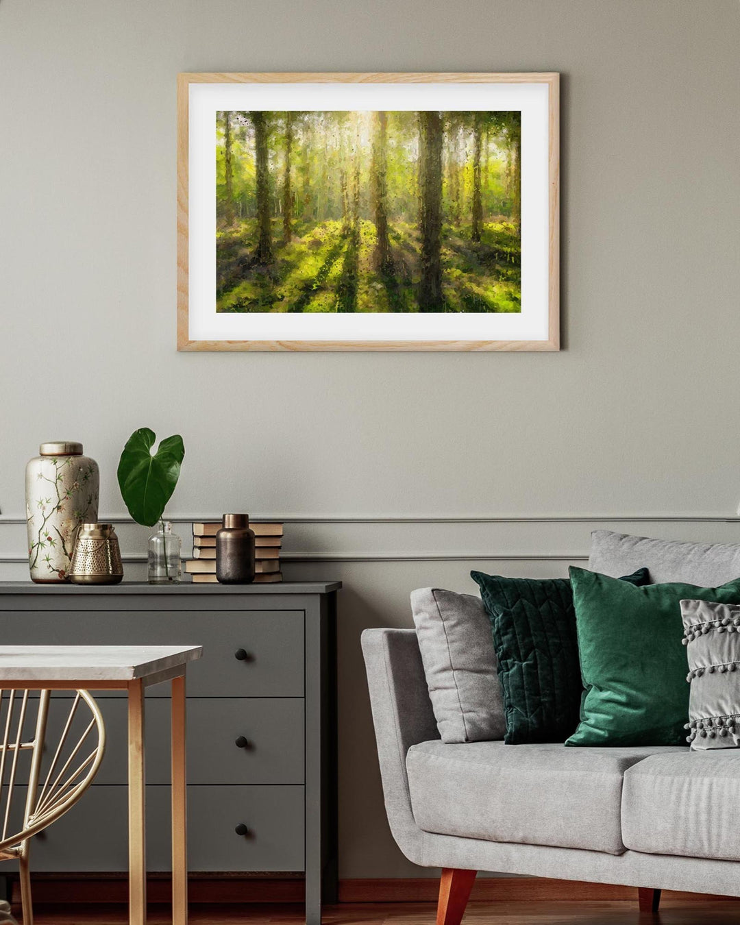 Framed artwork of a forest scene above a living room with a sofa and side table.