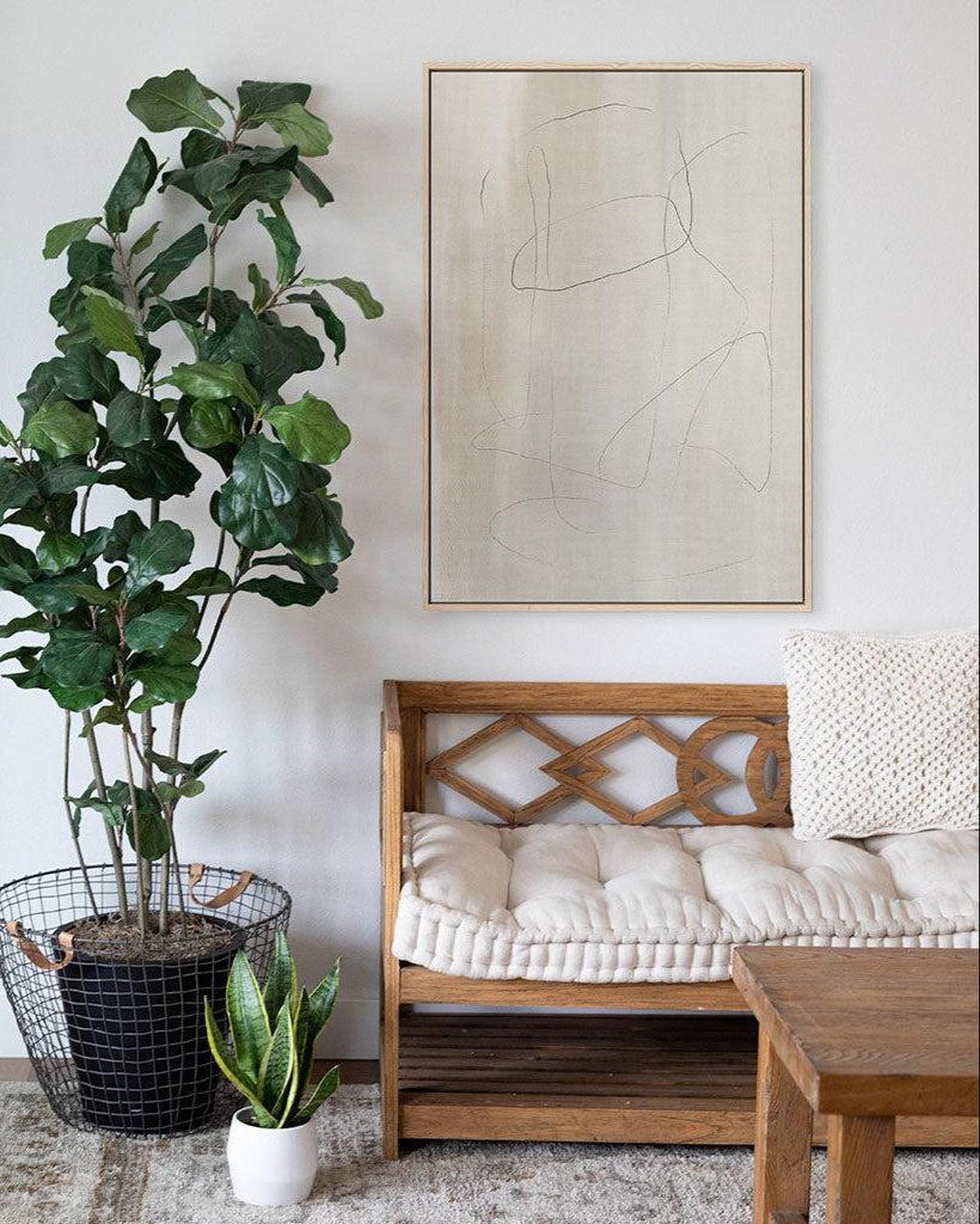 Living room with wooden bench, potted plants, and abstract art on the wall.