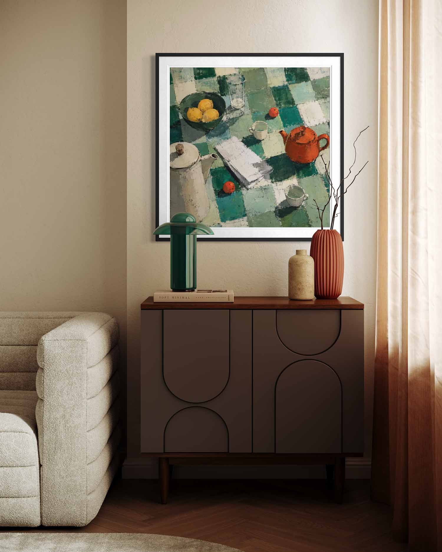 A framed still life painting with a green and teal checkered pattern hangs on a beige wall above a dark brown sideboard cabinet in a styled living room setting.