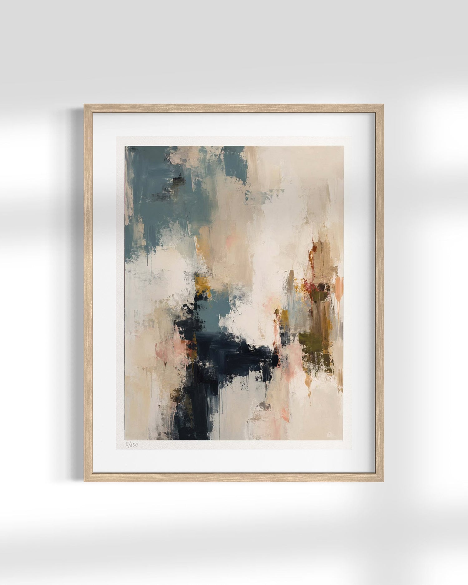A framed abstract art print featuring textured brushstrokes in beige, slate blue, charcoal, and soft orange, presented in a light natural wood frame with a white mat against a light gray wall.