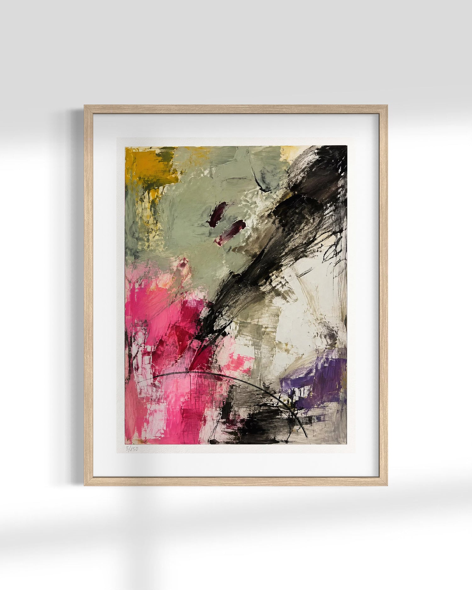 Framed abstract wall art featuring expressive brushstrokes in black, pink, purple, yellow, and gray on a white mat, set in a light wood frame against a white wall.