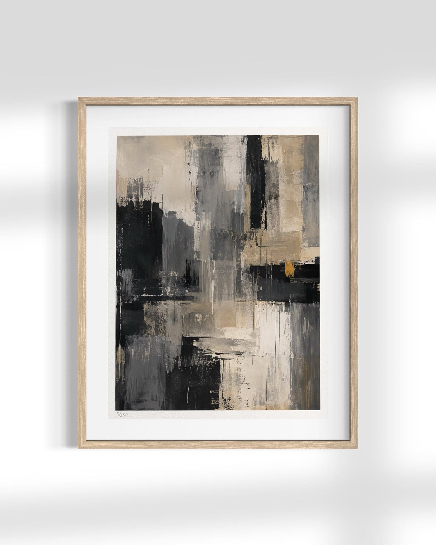 Abstract framed wall art featuring a modern composition of black, gray, beige, and white brushstrokes with a small gold accent, presented in a light wood frame with a white mat against a light gray wall.