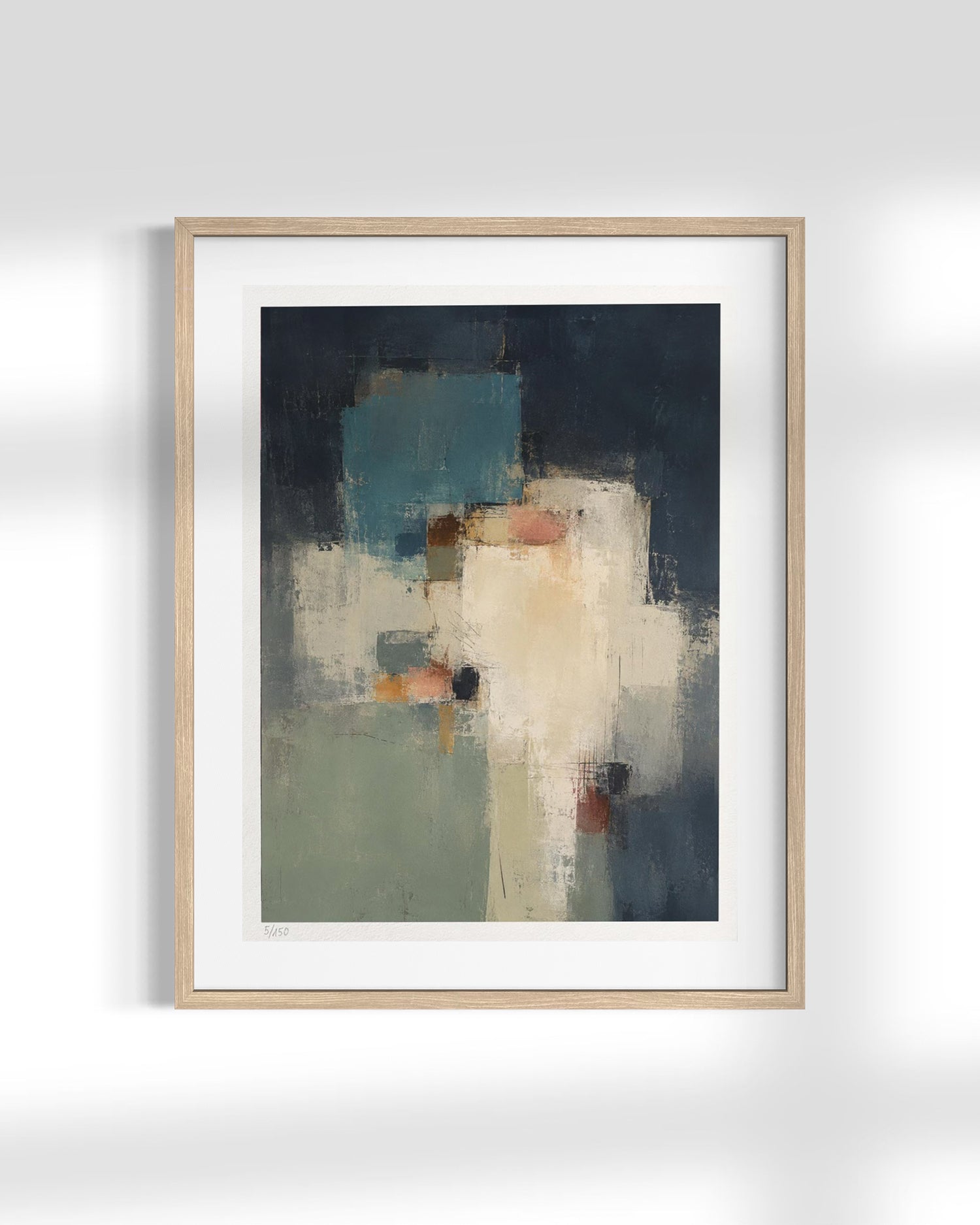 A framed abstract art print featuring a geometric composition in shades of navy, teal, cream, and sage green, set in a light natural wood frame with a white mat against a light gray wall.