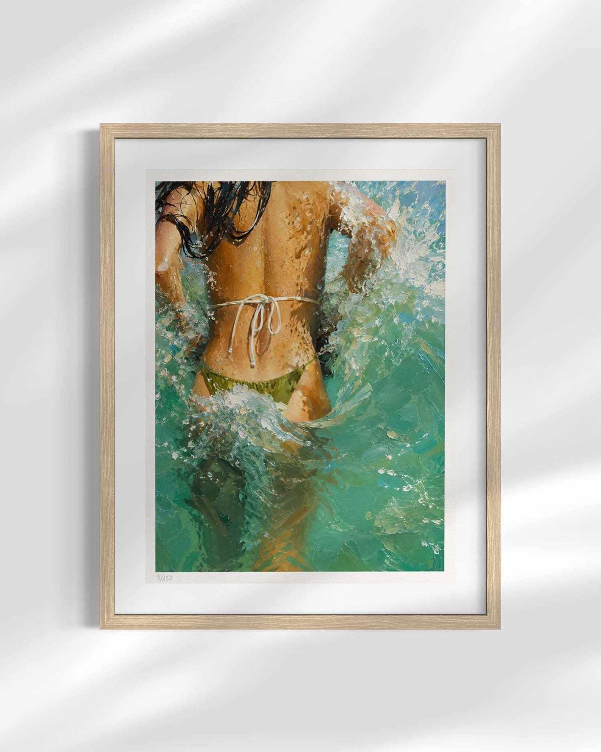 A framed art print featuring an impressionistic painting of a woman from behind in turquoise ocean water, displayed on a light gray wall with soft shadow overlays.