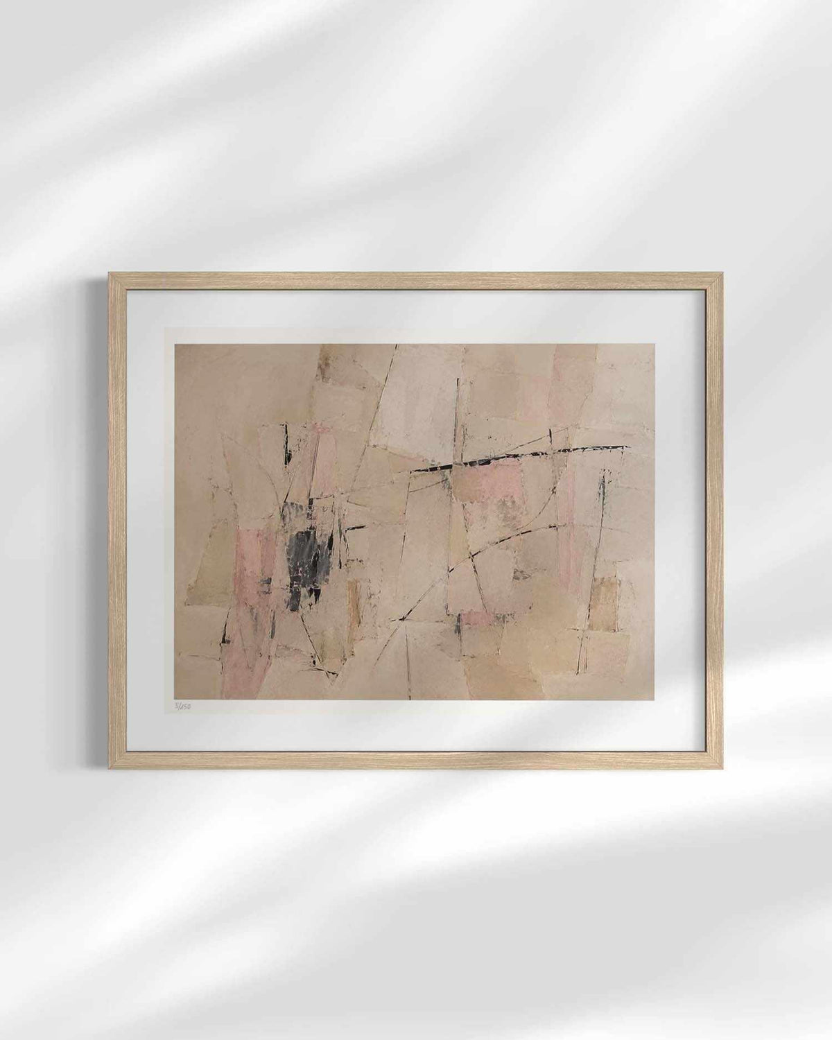 Framed abstract wall art hanging on a white wall, featuring soft beige, blush pink, and black brushstrokes with a light wood frame and white mat.