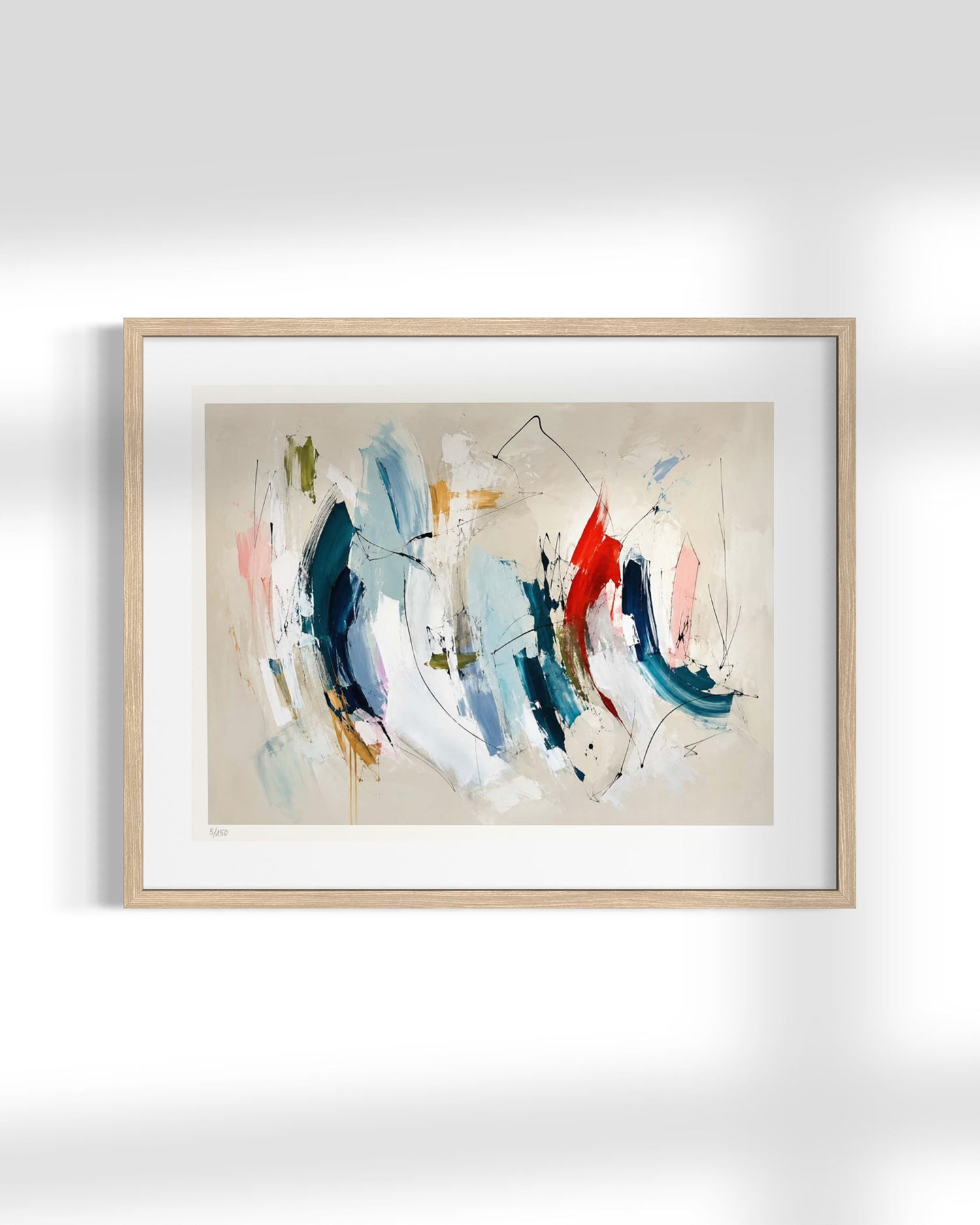 A framed abstract canvas print featuring expressive brushstrokes in blue, red, white, and beige, housed in a light natural wood frame with a white mat, displayed against a clean white wall.