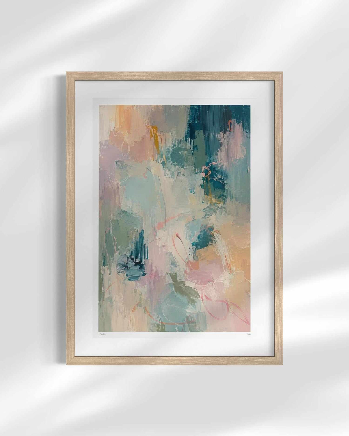 A framed abstract art print featuring a soft, painterly composition of teal, pink, peach, and cream brushstrokes, set in a light natural wood frame with a white mat against a white wall with soft shadow overlays.