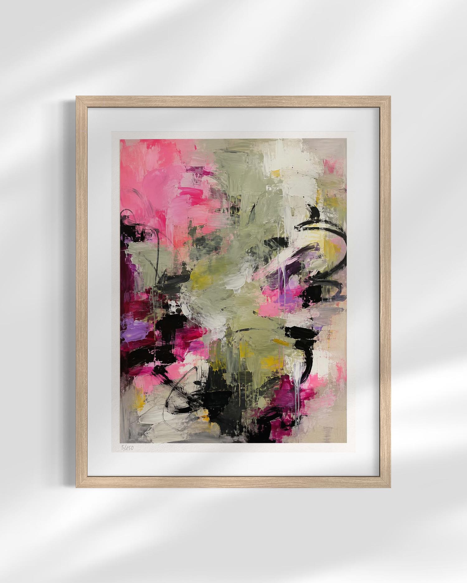 Framed abstract wall art print with expressive brushstrokes in pink, olive green, black, purple, and cream, shown in a light wood frame against a white wall with soft shadow overlays.