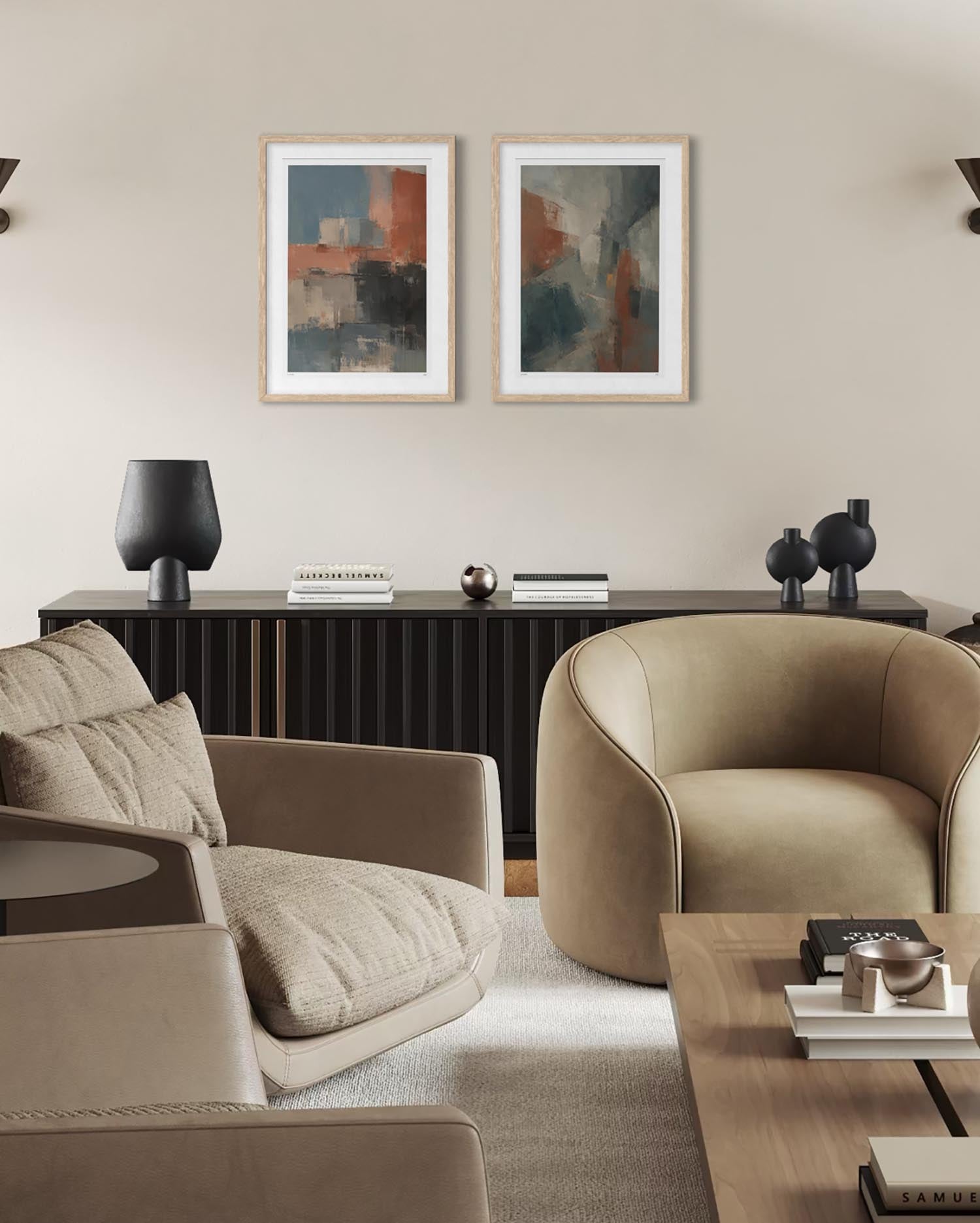 A styled modern living room featuring two abstract framed wall art prints hanging above a dark wood console. The room includes beige upholstered armchairs, a light wood coffee table, and a neutral beige wall.