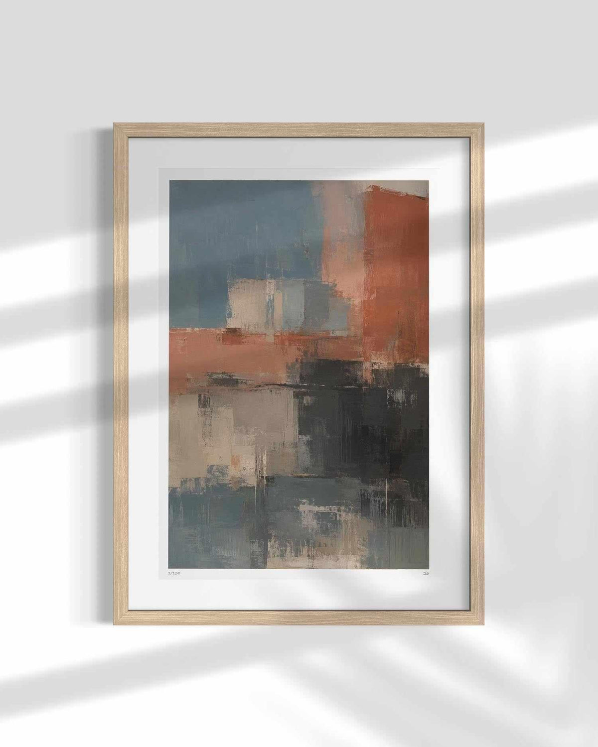 Framed abstract wall art hanging on a white wall, featuring a light wood frame, white mat, and an abstract painting with blocks of slate blue, terracotta orange, charcoal gray, and beige. Soft diagonal shadows from a nearby plant are cast across the print and wall.