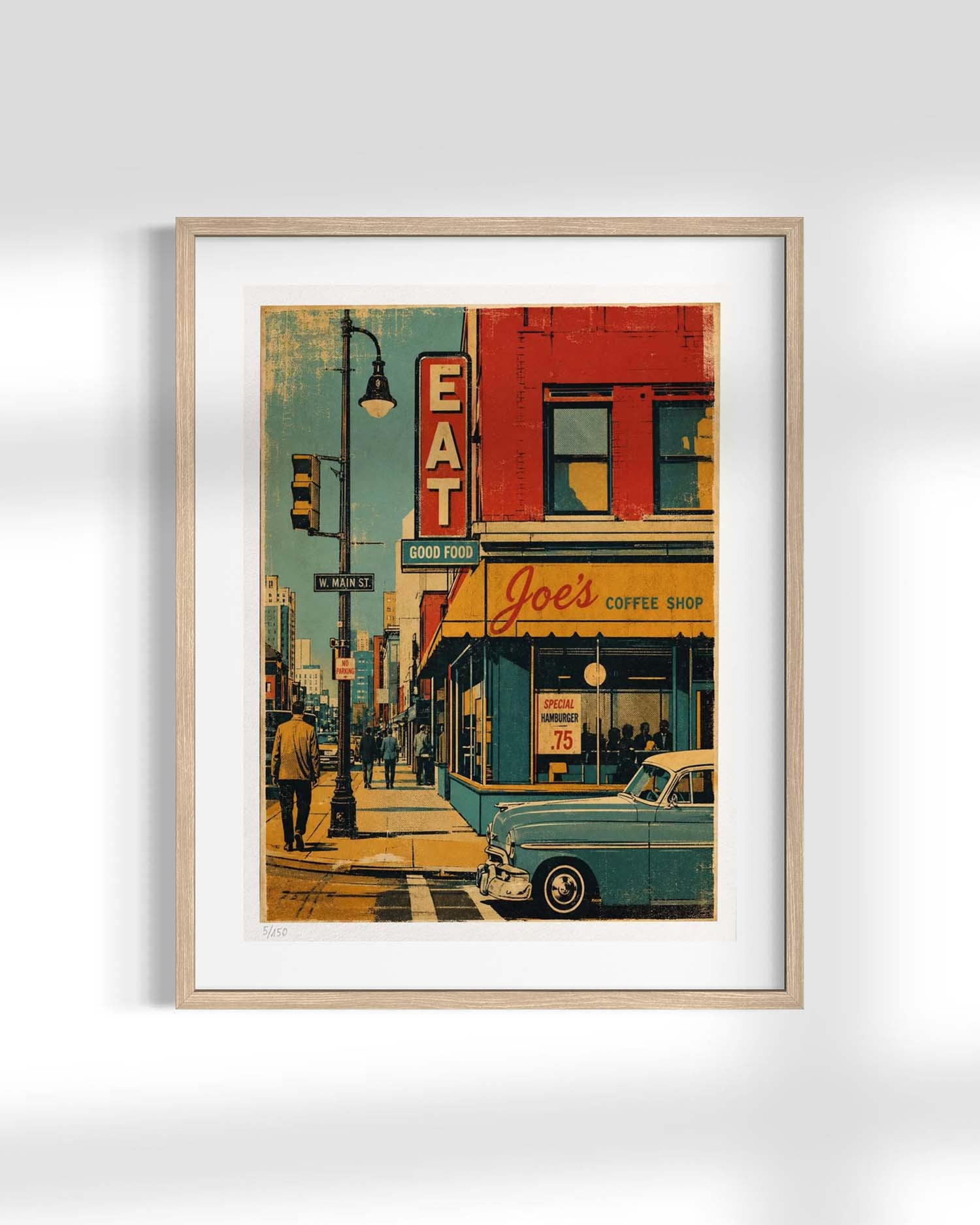 A framed art print depicting a retro street scene with a vintage blue car, a red brick building with 'Joe's Coffee Shop' signage, and a sidewalk with pedestrians, shown against a light gray wall.