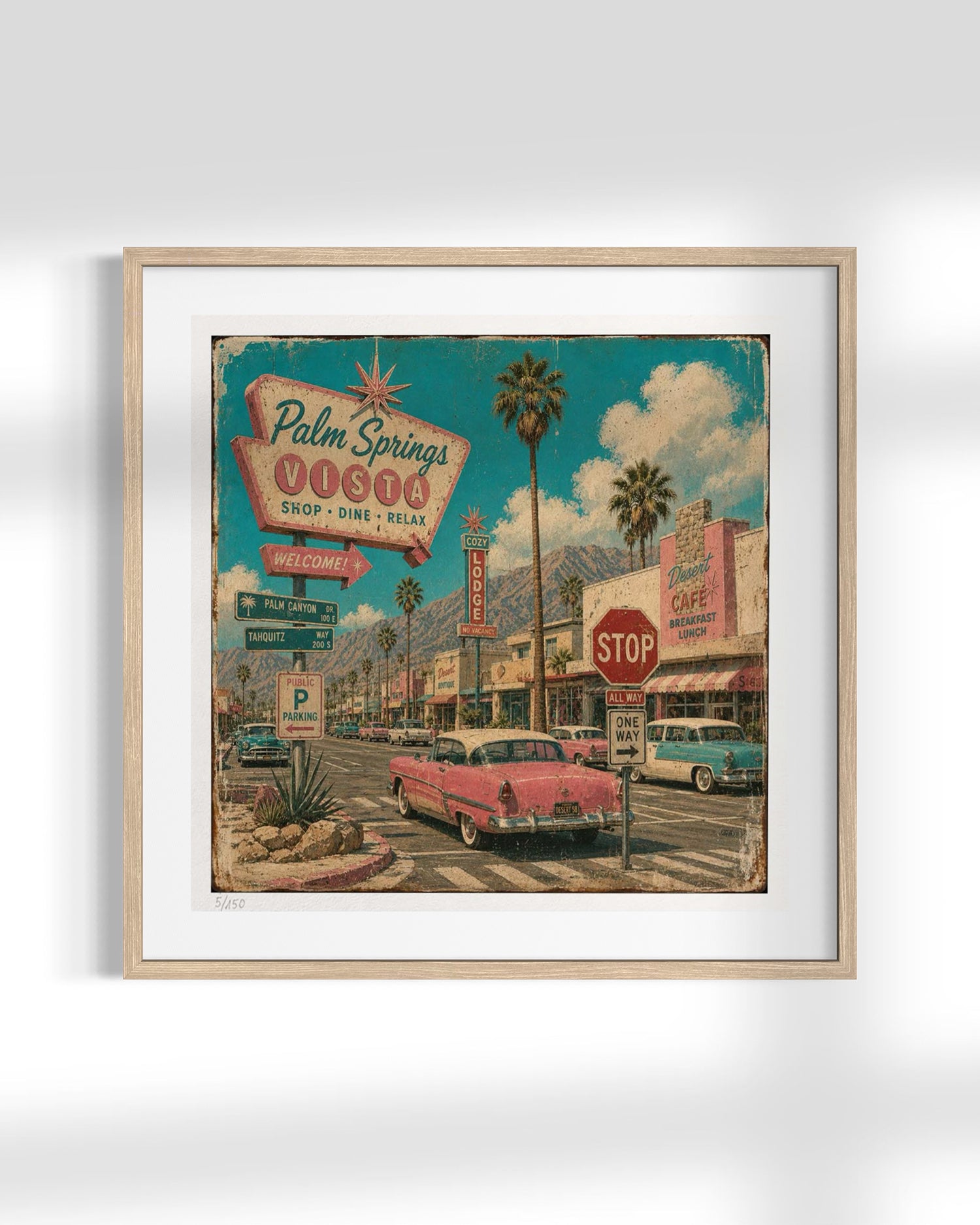 A framed art print depicting a retro 1950s Palm Springs scene with vintage cars, palm trees, and a colorful sign, mounted on a light gray wall.