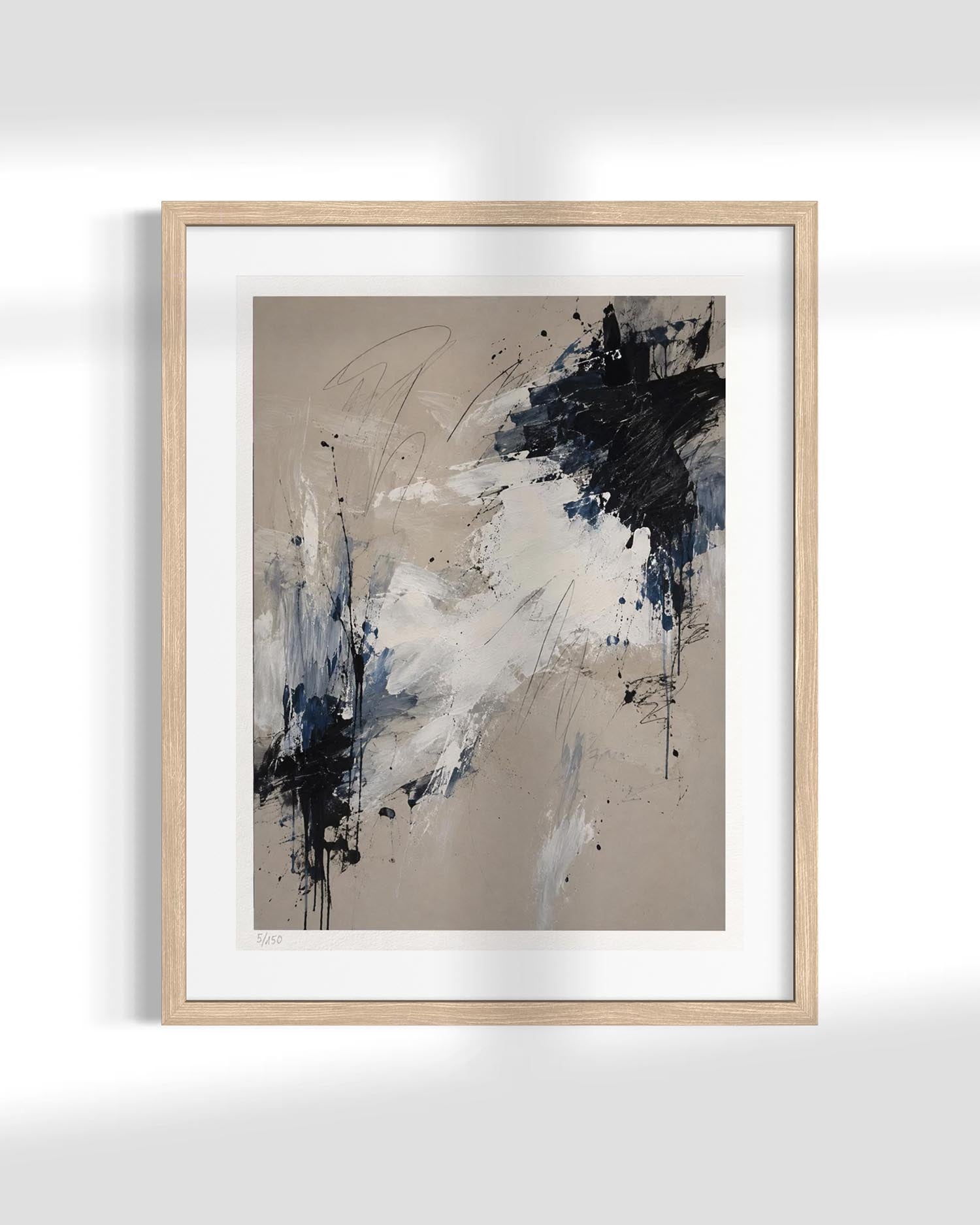 Framed abstract wall art featuring a beige background with expressive black, white, and blue brushstrokes, presented in a light natural wood frame against a white wall.