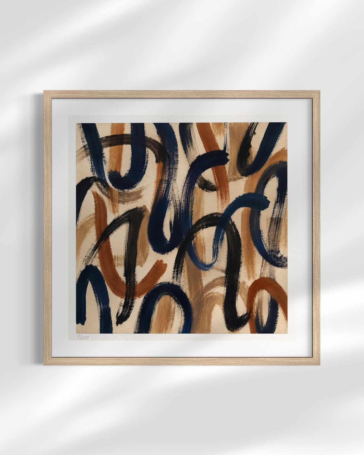 Framed abstract wall art featuring expressive navy and terracotta brushstrokes on a warm beige background, displayed in a light wood frame against a white wall with soft shadow overlays.