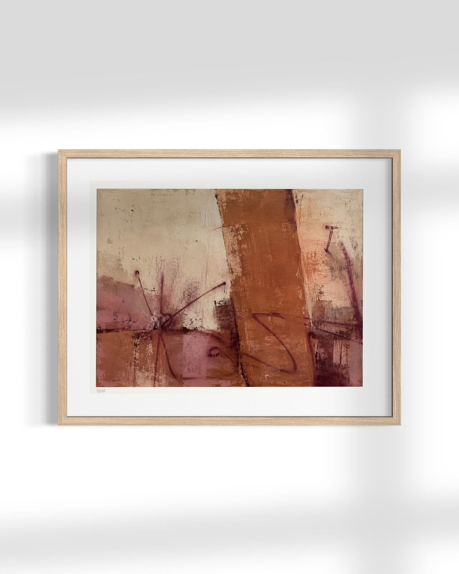 A framed abstract art print featuring earthy tones of terracotta, brown, and beige with textured brushstrokes, presented in a light wood frame with a white mat against a clean white wall.